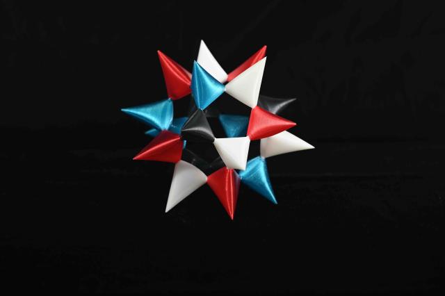 random 4-color assemblable Barth Sextic. Five cone-like structures in each of four colors (red, white, black, blue) assembled into a hollow 20-pointed star shape. random 4-color assemblable Barth Sextic. Five cone-like structures in each of four colors (red, white, black, blue) assembled into a hollow 20-pointed star shape.